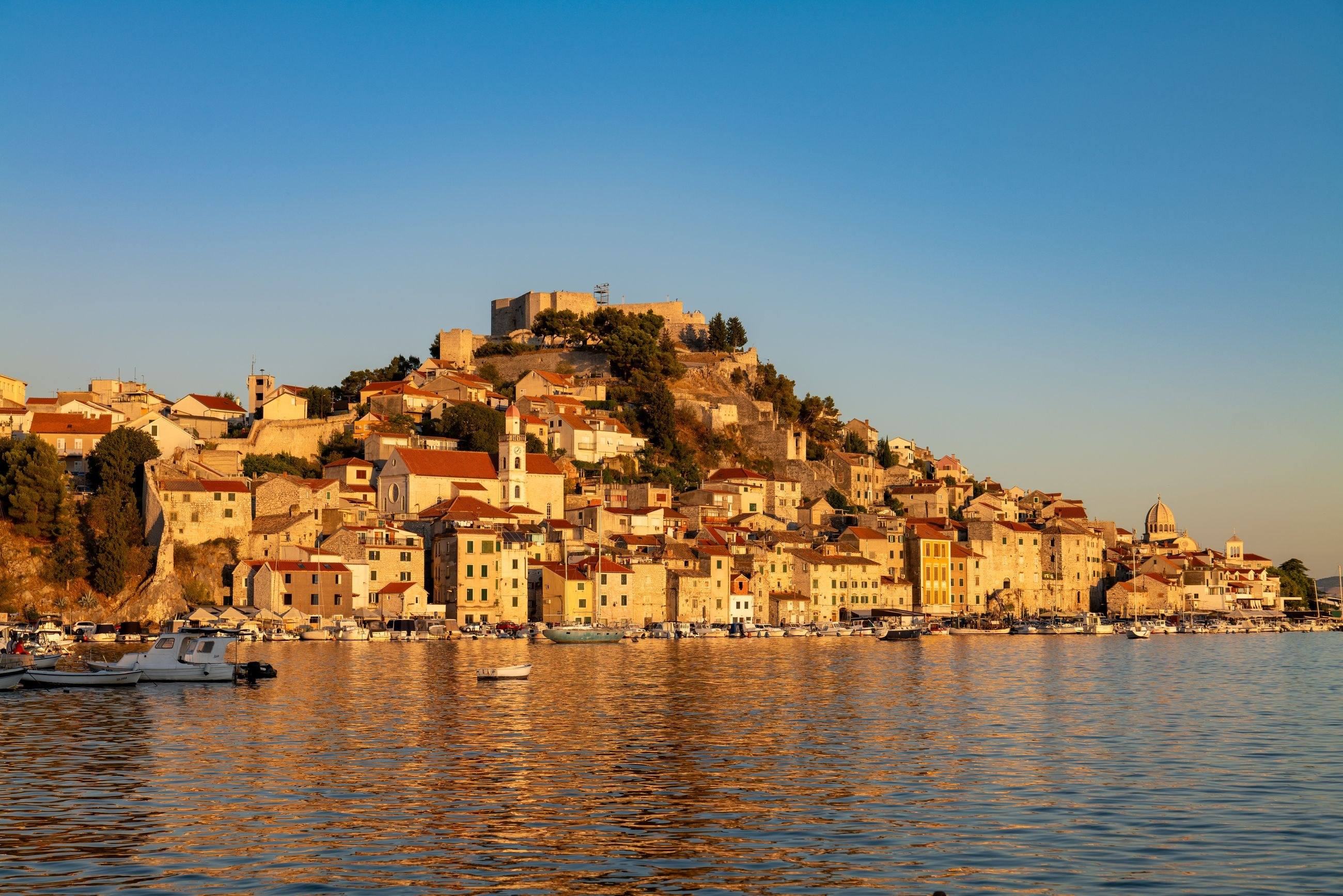 Šibenik’s old town and St Michael’s Fortress glowing in evening light above the harbour